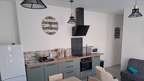 A modern kitchen with a wooden table, chairs, a built-in oven, a microwave, and a coffee maker.