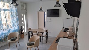 A modern kitchen with a microwave, kettle, and coffee maker. There is a dining area with a table and chairs.