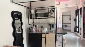 A compact kitchen with a microwave, sink, and bar stools. - BIG LITTLE HOTEL  (Denver)
