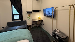A hotel room with a bed, a desk, a TV, and a wardrobe. - BIG LITTLE HOTEL  (Denver)