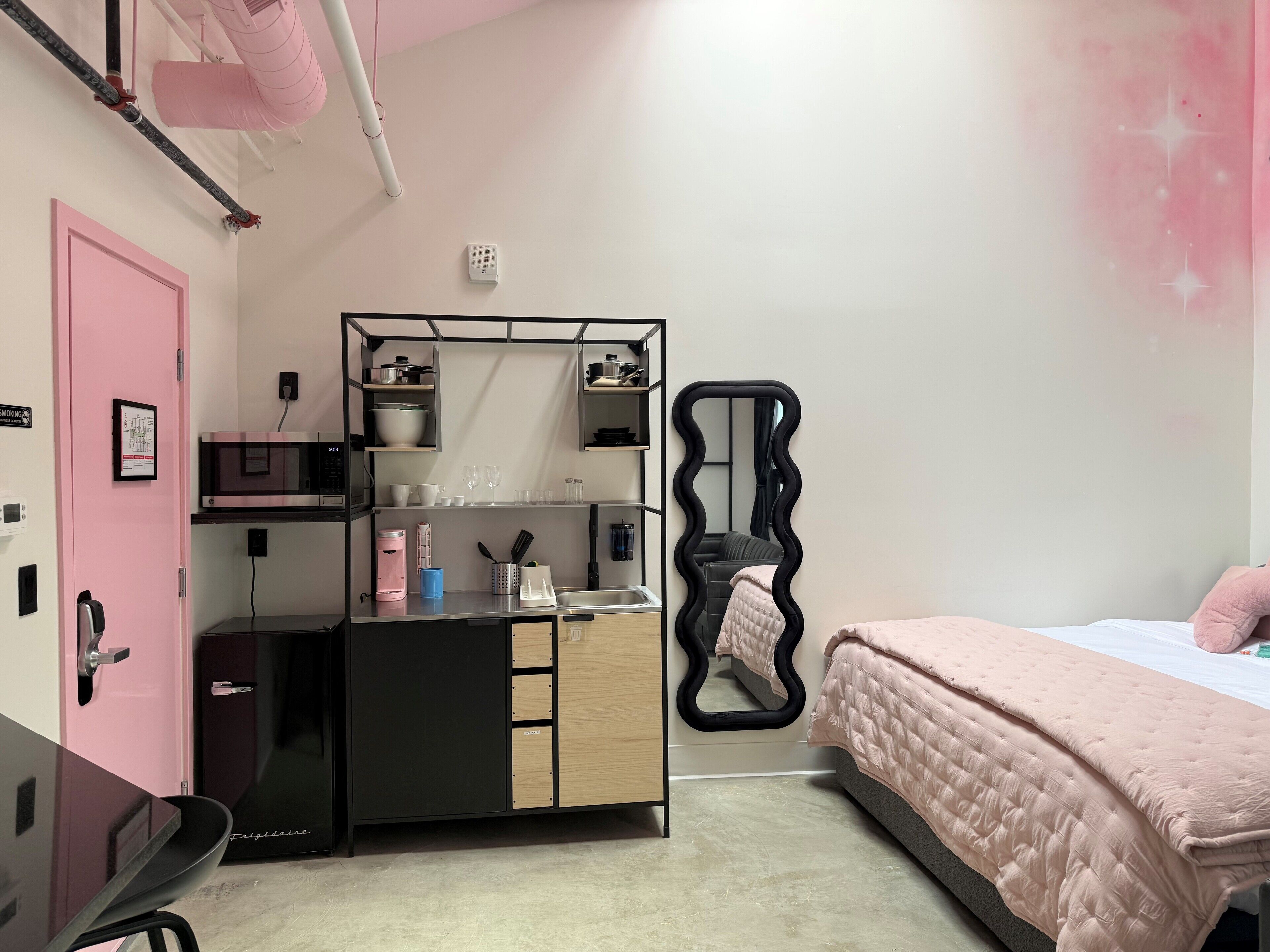 A bedroom with a bed, a dresser, a mirror, and a desk with a chair.