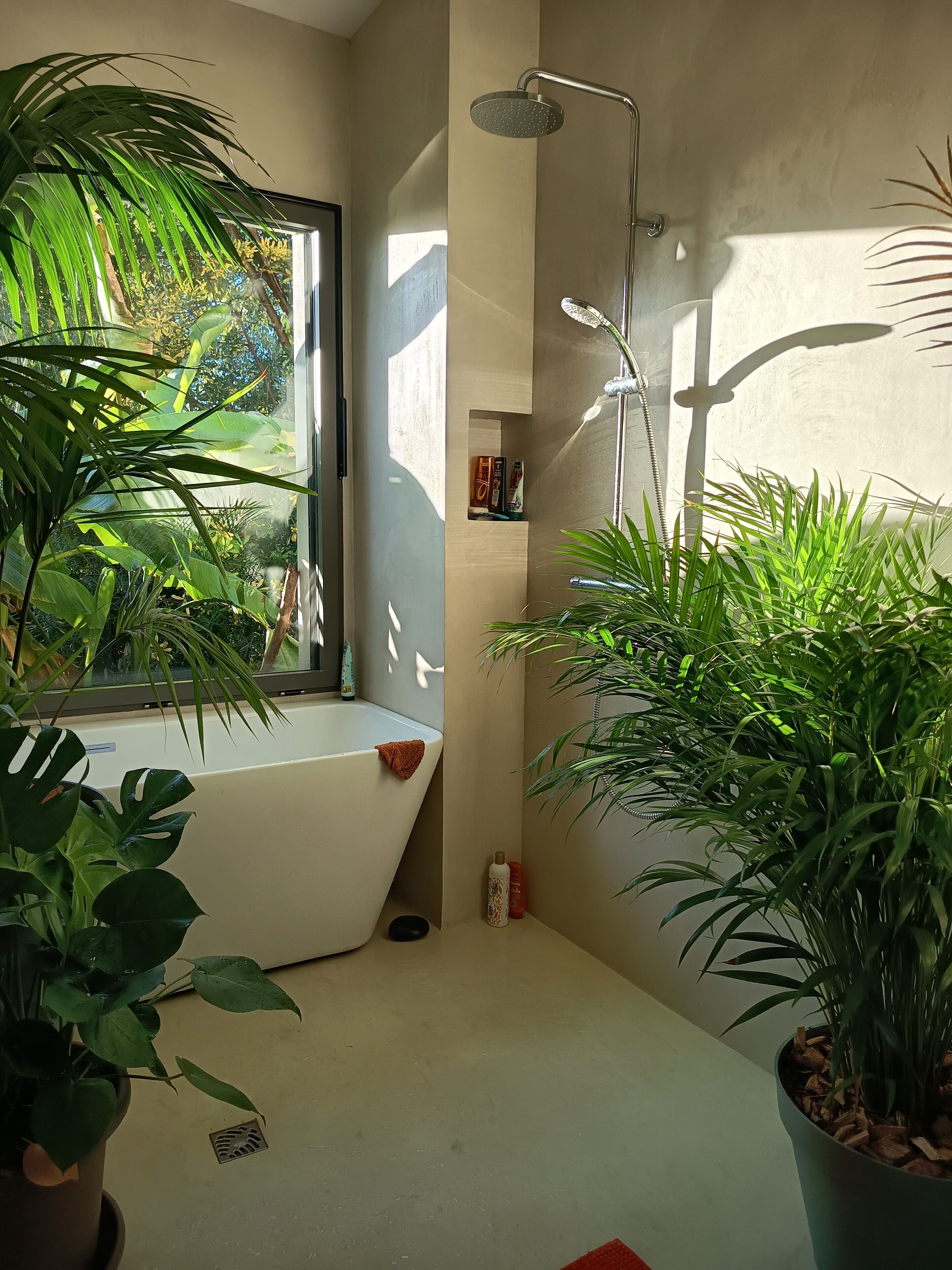 Een moderne badkamer met een badkuip, douche en potplanten.