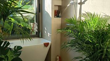 Een moderne badkamer met een badkuip, douche en potplanten.