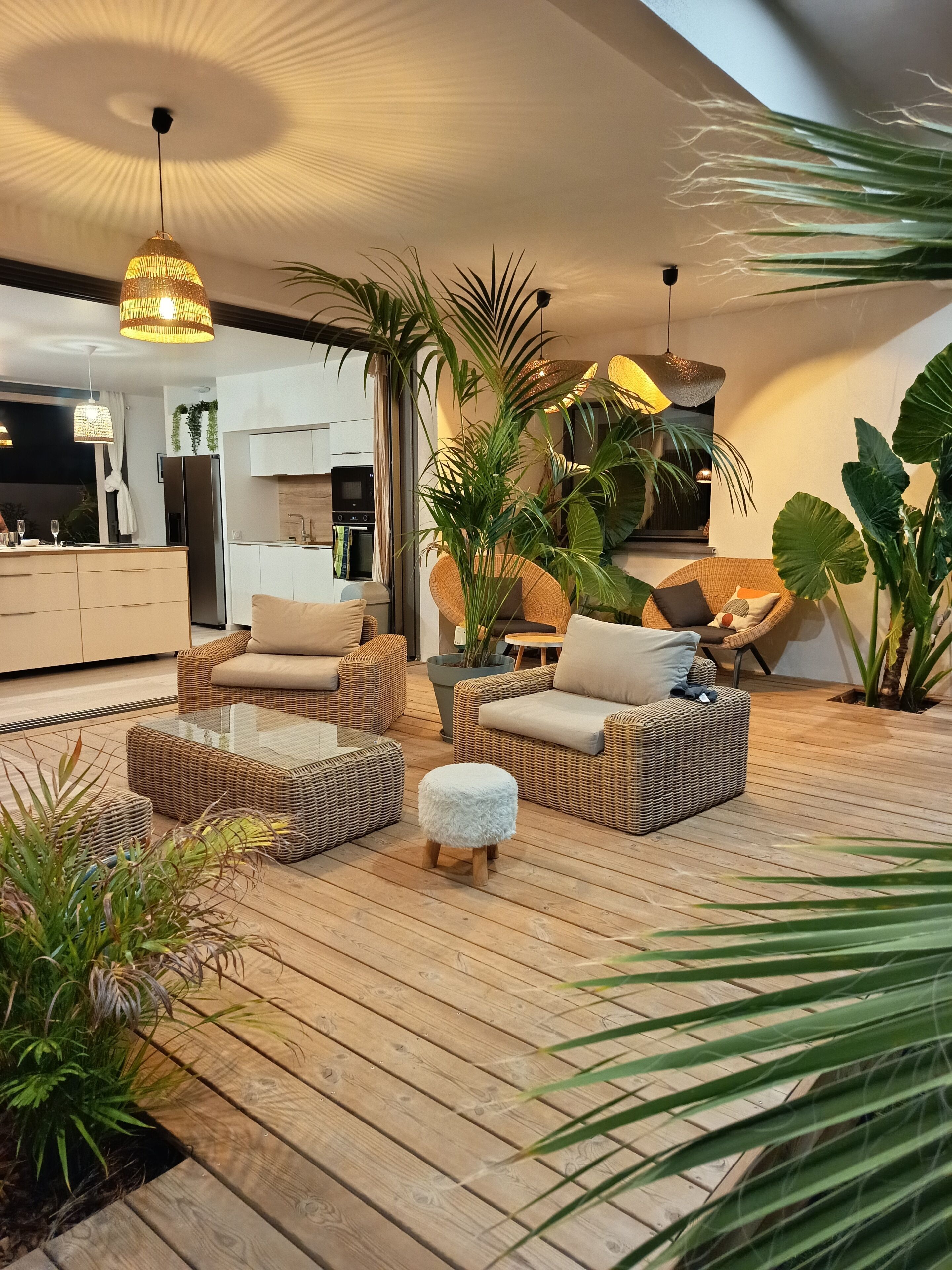 Un salon moderne avec des meubles en osier, une table basse en verre et un plancher en bois.