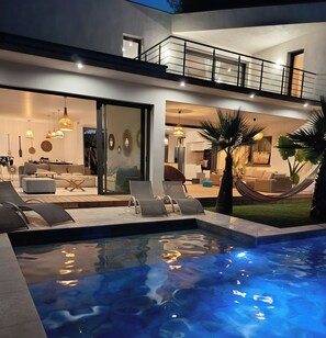 A modern house with a swimming pool, outdoor seating, and a well-lit interior. - CASA LUMA between the sea and Montpellier (Lattes)