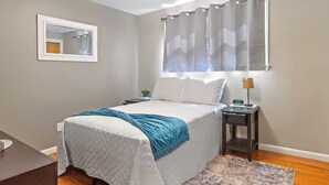 A bedroom with a bed, a nightstand, a lamp, a mirror, and a window with a curtain. - ⁂Pet-friendly⁂Fenced yard w/deck⁂Pool Table⁂ (Rapid City)