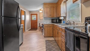 A kitchen with wooden cabinets, a black refrigerator, a microwave, and a sink. - ⁂Pet-friendly⁂Fenced yard w/deck⁂Pool Table⁂ (Rapid City)
