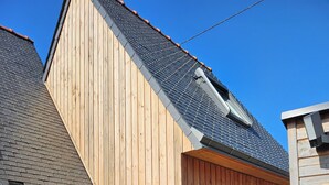A wooden house with a sloped roof, a small porch, and a window.
