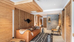A modern interior with a wooden wall, a sofa, a chair, and a fireplace.