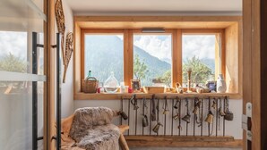 A rustic cabin with a wooden bench, a rustic wall decor, and a window with a view of mountains.