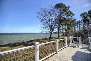 A waterfront promenade with a white fence, benches, and trees. - Charming Riverside Cottage w/Optional Guest House (Cobbs Creek)