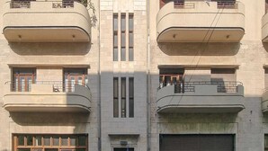 Un edificio de altura media con varios balcones, una entrada central y una puerta de garaje.