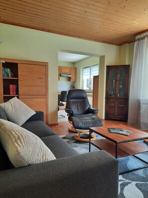 A living room with a sofa, a black leather chair, a wooden coffee table, and a cabinet with glass doors.