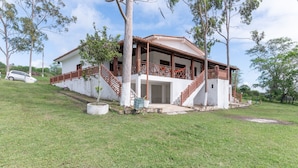 Una casa de dos pisos con balcón, una escalera y un pequeño jardín.