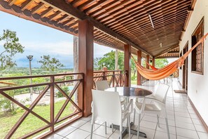A covered outdoor area with a table and chairs, a hammock, and a view of a pool and greenery. - Casa de Campo c Piscina 5 Quartos-SH106D (Sairé)