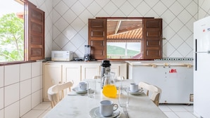 Una cocina con una mesa de comedor preparada para dos personas, microondas, licuadora y refrigerador.