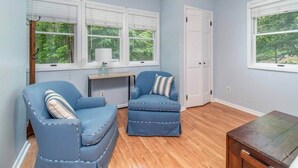 Une pièce avec deux fauteuils bleus, une table en bois et un bureau avec une lampe.