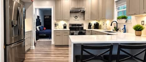 A modern kitchen with a central island, stainless steel appliances, and a dining area with black chairs.
