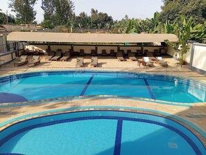 A swimming pool with lounge chairs and a covered seating area. - Sabby Grand Hotel (Thika)