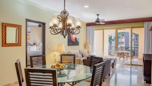 A dining area with a glass table and chairs, a chandelier, and a view of the outside.