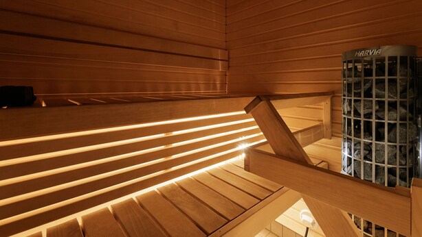 A wooden sauna with slatted benches and a stone heater. - Spacious 2BR Apt - Lake View & Sauna (Jyväskylä)