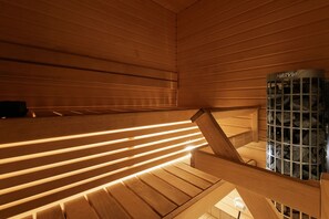 A wooden sauna with slatted benches and a stone heater. - Spacious 2BR Apt - Lake View & Sauna (Jyväskylä)