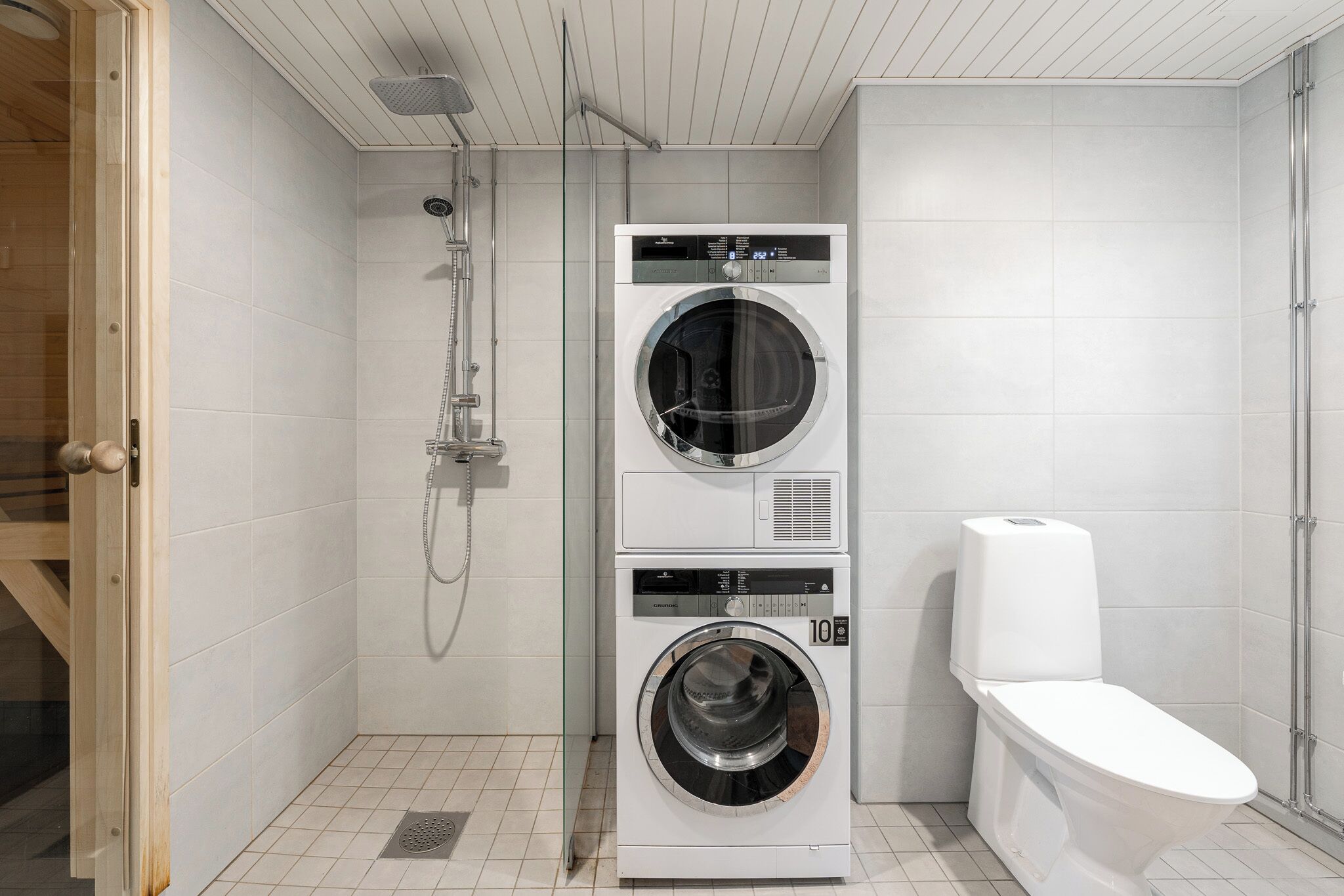 Ein kleiner Hauswirtschaftsraum mit Waschmaschine und Trockner, Toilette und Dusche.