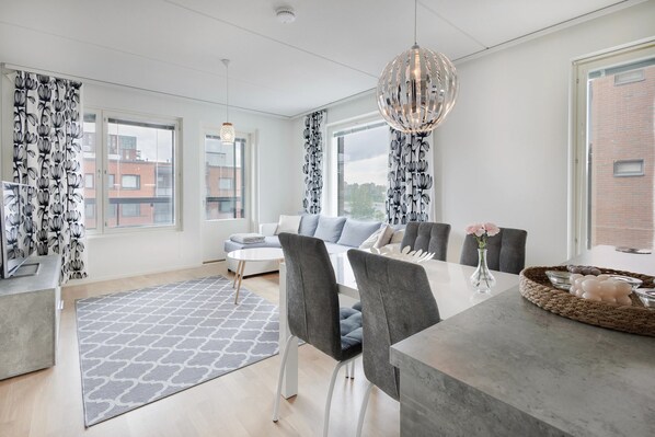 A modern living room with a sofa, dining table, chairs, and a chandelier. - Spacious 2BR Apt - Lake View & Sauna (Jyväskylä)