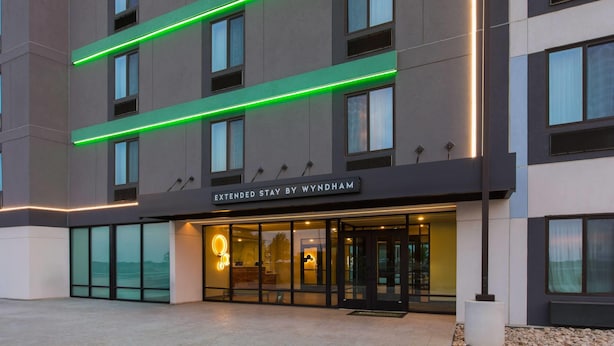 A modern hotel with a glass facade, a sign reading 'Extended Stay by Wyndham,' and a well-lit entrance.