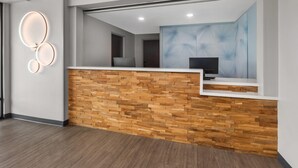A reception area with a wooden reception desk, a modern light fixture, and a large abstract painting on the wall.