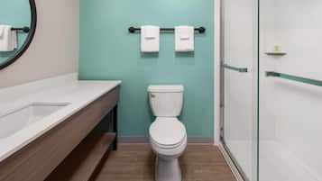 A bathroom with a toilet, a sink, a glass shower enclosure, and a towel rack with two towels.