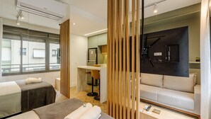 Una habitación de hotel moderna con un sofá, una mesa de masajes, un televisor montado en la pared y un escritorio con una silla.