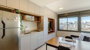 Una cocina moderna con microondas integrado, refrigerador de acero inoxidable y ventana con vistas a la ciudad.