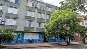 A multi-story building with air conditioning units, a mural on the lower wall, and a tree in front. - Comfortable ap 800 m From Redencao Park Eba0401 (Porto Alegre)