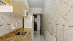 A narrow kitchen with granite countertops, a stainless steel sink, and a microwave. - Comfortable ap 800 m From Redencao Park Eba0401 (Porto Alegre)