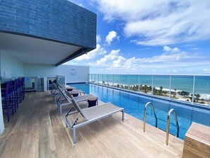 A rooftop pool with lounge chairs and a view of the ocean. - Apto c Wi-fi Academia sal o de Jogos e Garagem (Salvador)