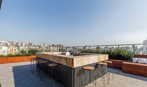 A rooftop bar with a marble counter, bar stools, and a seating area with cushions. - High-standard Studio in Moinhos Gos1007 (Porto Alegre)