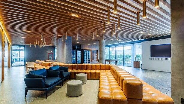 A modern lounge area with leather seating, a large window, and a wooden ceiling. - High-standard Studio in Moinhos Gos1007 (Porto Alegre)