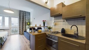 Cocina compacta con horno integrado, un lavamanos y una pequeña zona de comedor con banco.