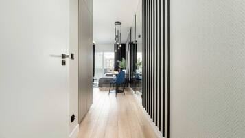 A modern hallway with a wooden floor, a dining area with a table and chairs, and a view of buildings outside.