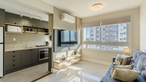 A modern kitchen with built-in appliances, a flat-screen TV, and a dining area with a sofa and cushions.