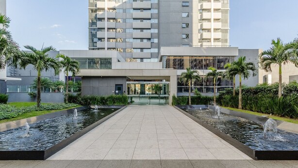 A modern building with a central entrance, surrounded by water features and palm trees.