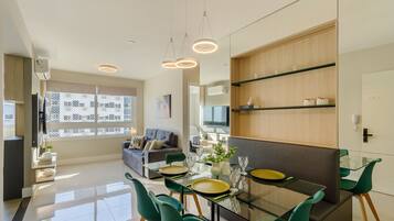Uma sala de estar moderna com uma mesa de jantar de vidro, cadeiras verdes e um sofá.