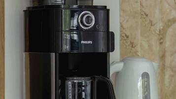 Une machine à café noire de marque Philips est posée sur un comptoir en bois, à côté d’une bouilloire électrique blanche.