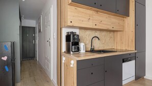 A modern kitchen with a wooden countertop, a coffee maker, a sink, and a dishwasher. - Comfortable Apartment | Balcony | Close to Silesian Park (Katowice)