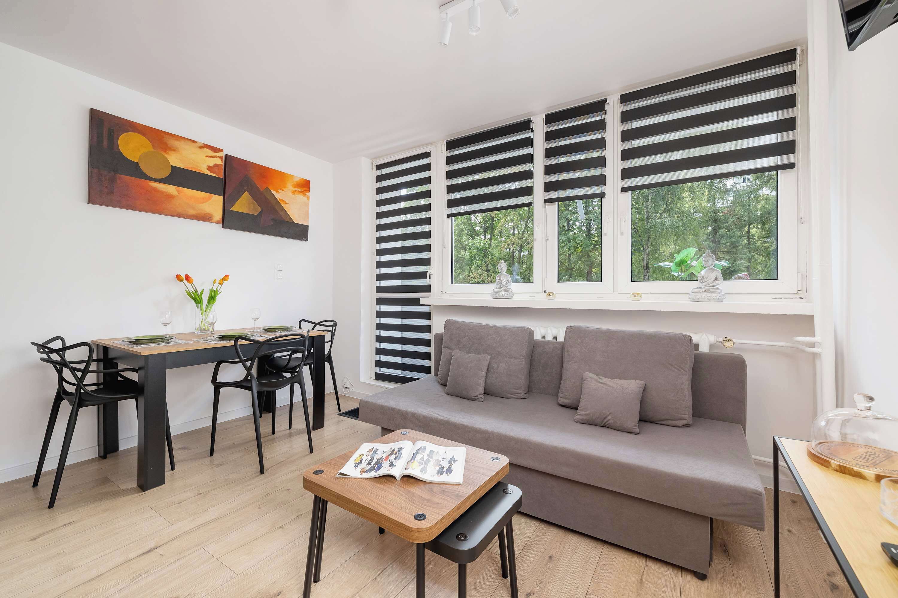 Living room with a sofa bed, TV, dining area and access to balcony.