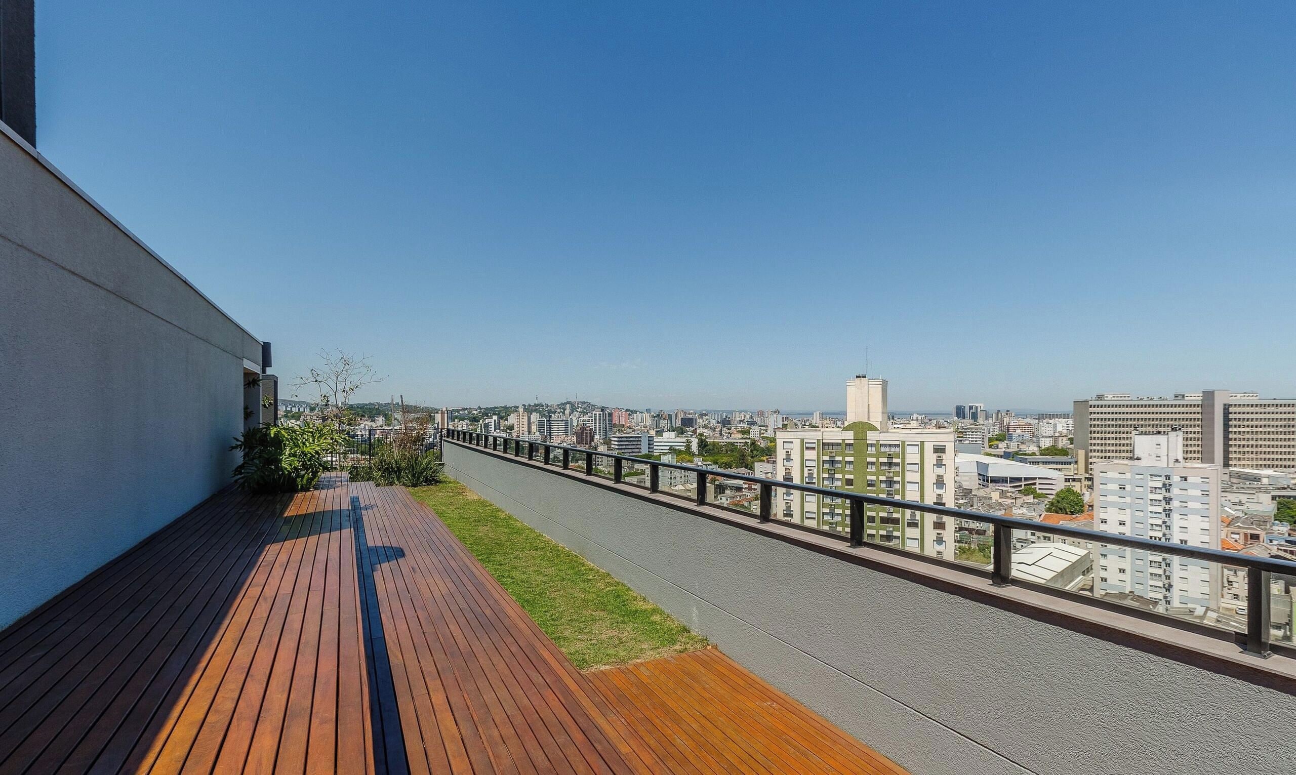 Un balc ón con cubierta de madera y baranda metálica que da a una vista panorámica de la ciudad.