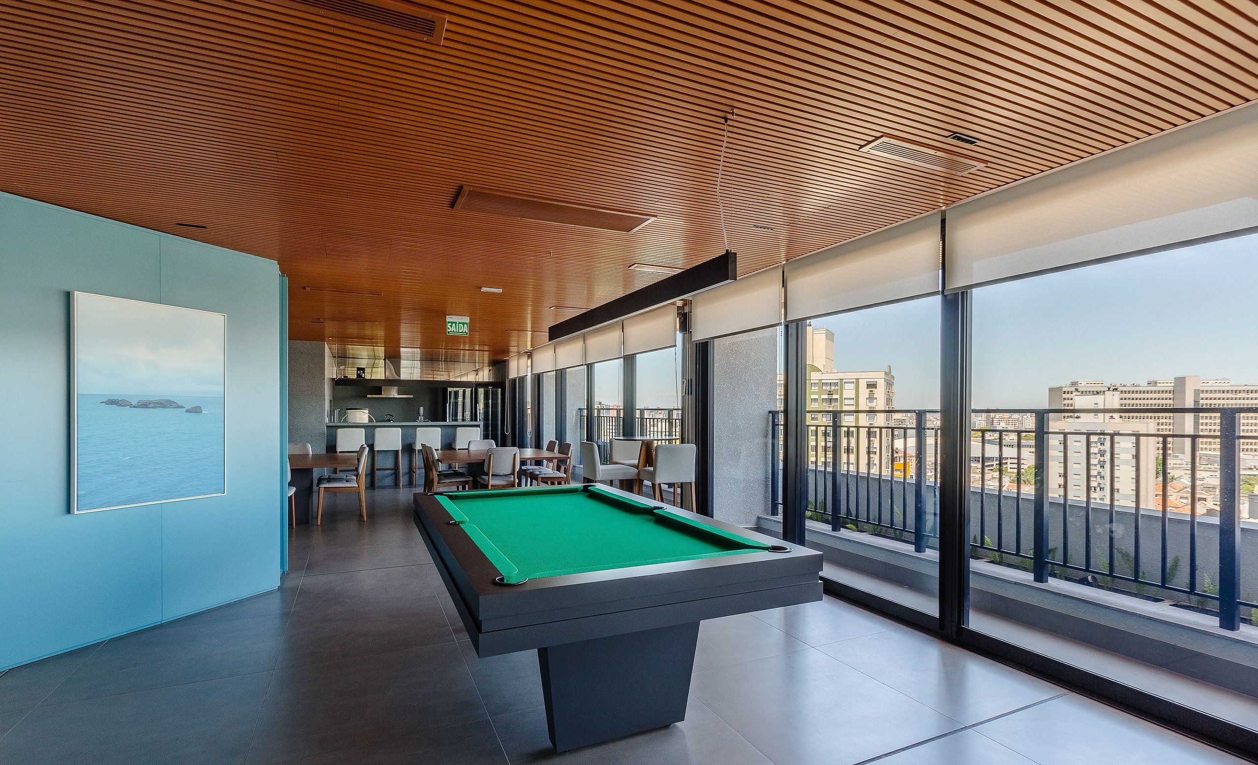 A pool table in a modern room with large windows and a view of the city.