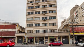 A multi-story building with a flat facade, several ground-level shops, and a visible storefront with signage. - Practical Studio Near Farroupilha Park Hpn707 (Porto Alegre)