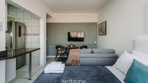 A modern hotel room with a kitchenette, a dining area, a sofa bed, and a TV. - Practical Studio Near Farroupilha Park Hpn707 (Porto Alegre)
